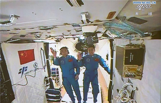 Photo taken on Oct. 19, 2016 shows the screen at the Beijing Aerospace Control Center showing the two Chinese astronauts Jing Haipeng (L) and Chen Dong waving hands in the space lab Tiangong-2. The two astronauts onboard the Shenzhou-11 spacecraft entered the space lab Tiangong-2 Wednesday morning. (Xinhua/Ju Zhenhua)