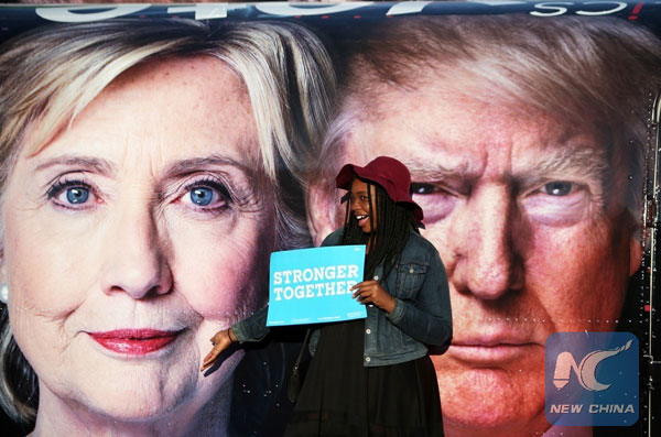 A girl poses for photos with Hillary Clinton and Donald Trump posters at Hofstra University in New York, the United States on Sept 26, 2016. (Photo/Xinhua)