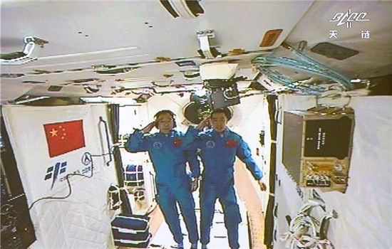 Photo taken on Oct. 19, 2016 shows the screen at the Beijing Aerospace Control Center showing the two Chinese astronauts Jing Haipeng (L) and Chen Dong saluting in the space lab Tiangong-2. (Xinhua/Ju Zhenhua)