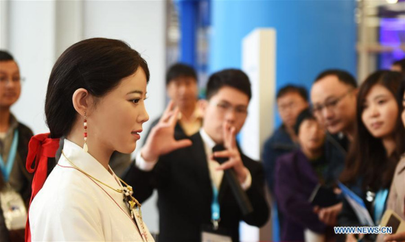 Visitors view an intelligent robot at the 2016 World Robot Exhibition in Beijing, capital of China, Oct. 21, 2016. The exhibition is held from Oct. 21 to 25 as part of the World Robot Conference. (Photo: Xinhua/Li Wen)