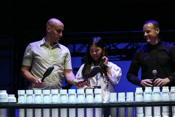Meridian (left), captain of the Blue Man Group performers, shows a journalist how to play music with a PVC piano. (Photo provided to China Daily)