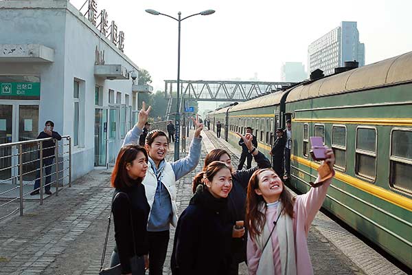 Students from Macao, who are studying in Beijing, take photos at Qinghuayuan Railway Station as their train makes a stop at the station on Tuesday.Zou Hong / China Daily