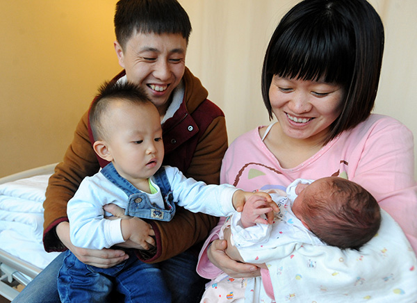 A couple both born after 1990 hold their children, an infant daughter and her 18-month-old elder brother, in Shenyang, Liaoning province, on Jan 3.Many couples responded to the chance to have a second child after policies were eased. LIHAO/CHINA DAILY