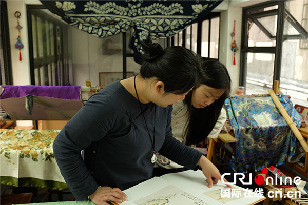 File photo shows Jin Jiahong instructing a student on traditional Hangzhou embroidery in May 2015. (Photo/CRI Online)