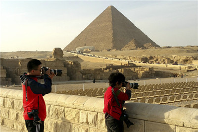 Chinese visitors take pictures of the Giza pyramids in Egypt. (Photo by Du Du/China Daily)