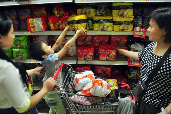 A boy jumps to take a package of instant noodle in a supermarket in Ningbo, Zhejiang province. (Photo by Hu Xuejun/For China Daily)