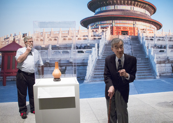 James Watt (left), curator emeritus and former chairman of Asian art at the Metropolitan Museum of Art in New York, talks about the uniqueness of Gourd Vase With Design of Scrolling Lotus made of mold-grown gourd from the Qing Dynasty (1644C1911) at the exhibit preview of Emperors' Treasures on Wednesday in Houston. MAY ZHOU / CHINA DAILY 