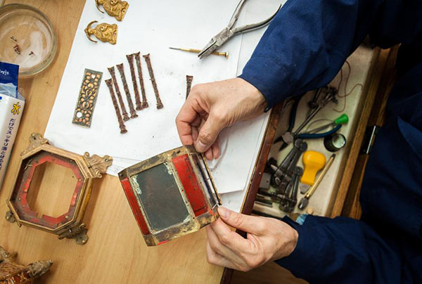 A craftsman dismantles a timepiece before repairing it in their office in the Palace Museum in Beijing, April 7, 2016. (Photo/Xinhua)