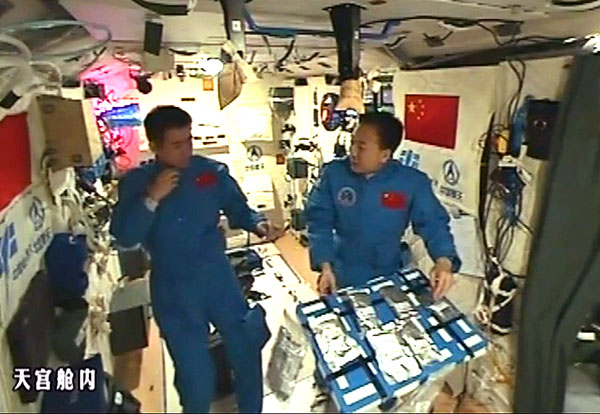 Astronauts Jing Haipeng (right) and Chen Dong display the meals they eat aboard the Tiangong II space lab. (Photo/Xinhua)
