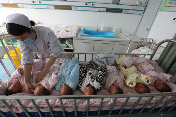 A nurse changes babies' clothing at a hospital in Xiangyang city, Hubei province, in February. Many of the newborns are their parents' second child. (Photo by Gong Bo / For China Daily)