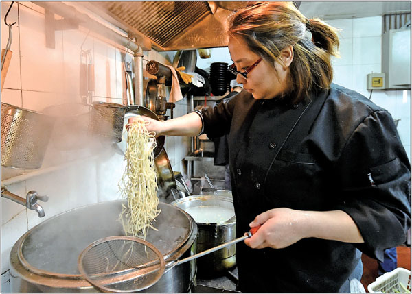 Zhang Ziyu prepares food for customers at the noodle restaurant she owns in Beijing. Even though she does not hold Beijing hukou, the Chongqing native has been pursuing her dreams in the capital city for four years.Photos By Cao Yang / For China Daily