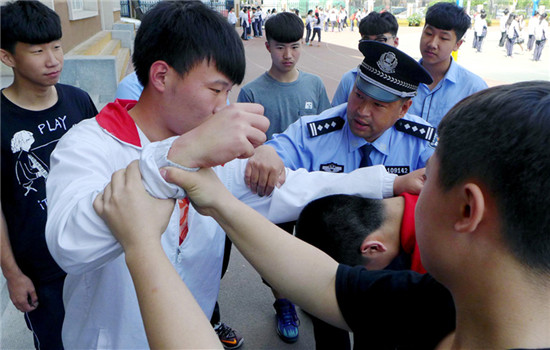 A police officer teaches students how to avoid being bullied during an awareness-raising class at a middle school in Shenyang, Liaoning province. (Photo by ZHAO JINGDONG/CHINA DAILY)