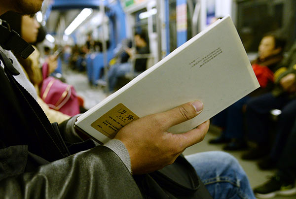 A passenger reads one of 40 books placed inside the light-rail system in Chongqing by author and bookstore owner Jiang Lin. (Photo provided to China Daily)