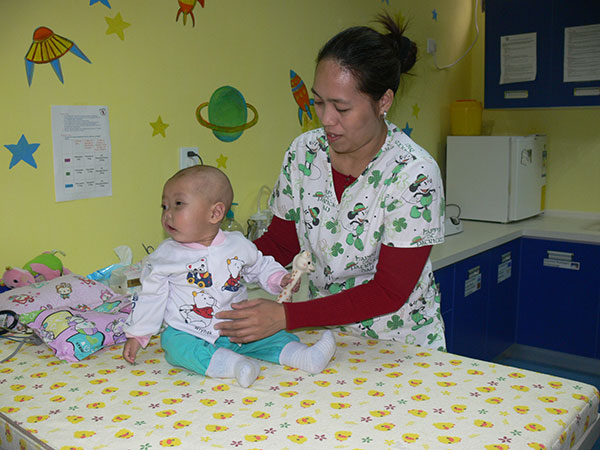 Sophie, a cancer patient who died last year, with a pediatric nurse at the Butterfly Home. Lyn Gould For China Daily