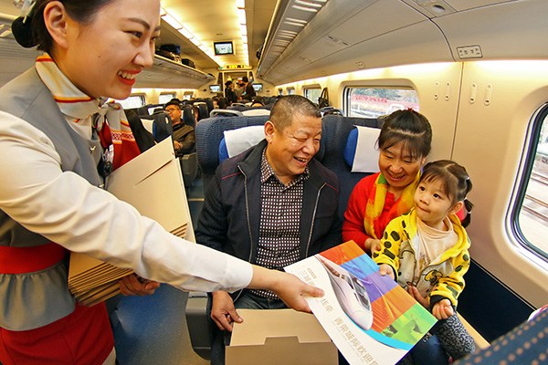 An attendant hands a commemorative envelope to passengers on the maiden trip of the Qingdao-Rongcheng high-speed rail in Shandong province on Wednesday. TANG KE/CHINA DAILY