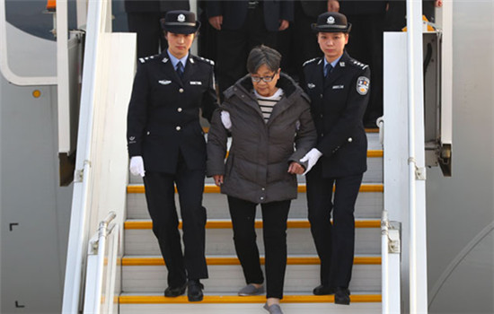 Yang Xiuzhu, accused of embezzling $36.3 million, is escorted from a plane after arriving in Beijing from the United States on Wednesday.(Yin Gang / Xinhua)