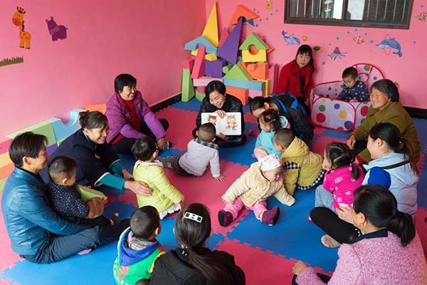 Volunteers play with left-behind children at a community-based early childhood development (ECD) center in in Wangjiaping village, Hubei province, Nov 11, 2016. [Photo/Xinhua] 