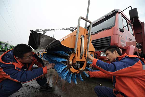 Sanitation workers fine-tune a road-clearing machine on Sunday to prepare for snow in Beijing.Lin Hui / For China Daily