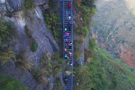 Children climb a steel ladder leading to the cliff village in Sichuan province on Saturday, November 19, 2016. (Photo/Beijing News)