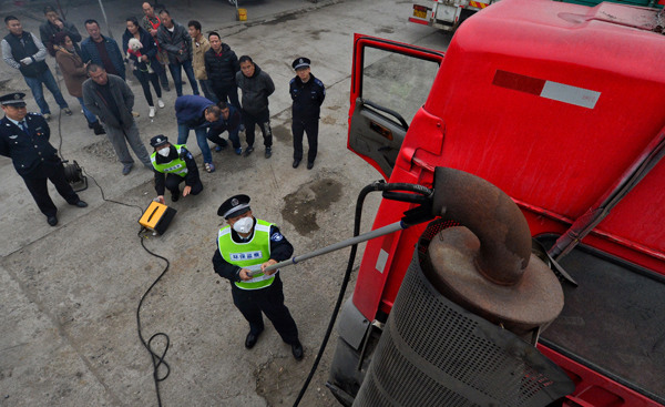 Environmental inspectors check the exhaust of a truck at a logistics park in Beijing's Tongzhou district this month.(Photo by Guo Qian/For China Daily)