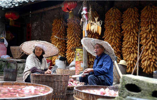 Lang Wencai (right), 56, cleans sweet potatoes in the rain with his wife in Yumuzhai.