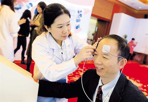 A conference delegate tries out a sensor system used in traditional Chinese medicine.(Xinhua)