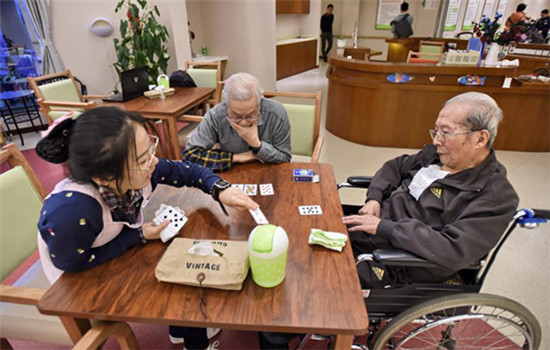 A worker plays cards with seniors at a nursing home in Beijing's Fengtai district on Nov 21, 2016. (Photo/Xinhua)