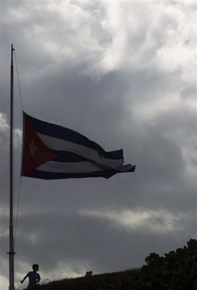 A boy stands below a Cuban national flag at half-mast in honor of Cuban revolutionary leader Fidel Castro, in Havana, capital of Cuba, on Nov. 27, 2016.  (Photo: Xinhua/David de la Paz)