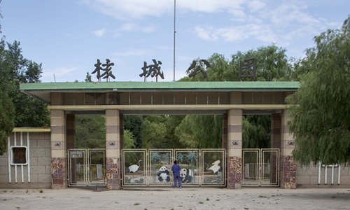 A woman looks through the rusty gates of an abandoned park in the center of 404. (Photo/Courtesy of Xu Haifeng)