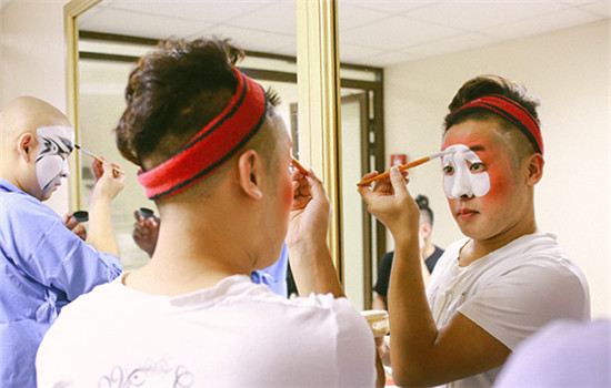 A performer paints his face for a role before a show.(Photo provided to China Daily)