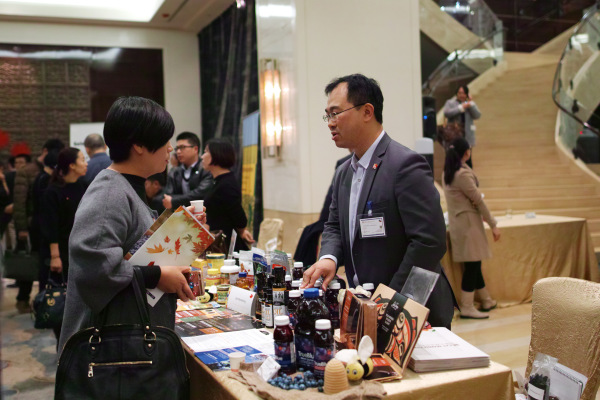 A business representative talk with a visitor at the Canadian agri-food export-cafe held in Beijing on Novermer 4, 2016. (Photo: Guosheng/Provided to Ecns.cn)