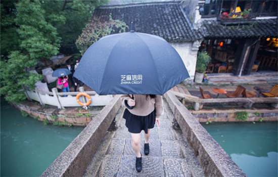 A tourist walks on a bridge with an umbrella borrowed via Zhima Credit, which is under Alibaba's affiliate Ant Financial, in Wuzhen, Zhejiang province, Nov 17, 2016. (XU KANGPING / FOR CHINA DAILY)