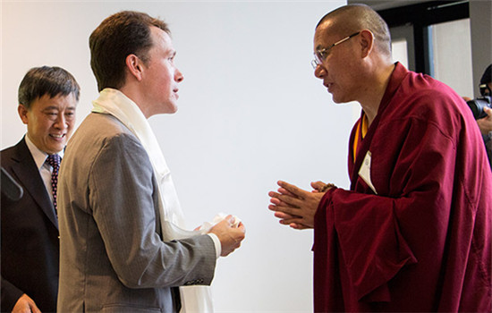 Tibet Living Buddha Dawaciren (right) presents a hada to Hans Stockton, director of the Center of International Studies at University of St. Thomas, while Lu Guangjin (left), director from the Information Office of the State Council, looks on.(Photo/chinadaily.com.cn)