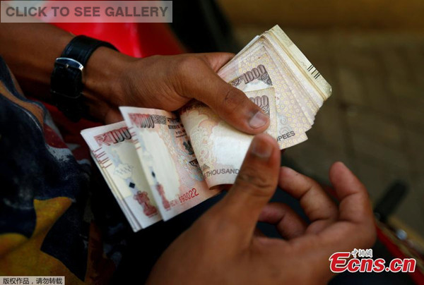 A man counts 500 and 1000 Indian rupee banknotes outside a branch of Bank of India in Mumbai, India, November 10, 2016. India Tuesday night abolished currency notes of 500 and 1,000 denomination in one of the biggest revolutionary monetary reforms since independence, aimed at curbing the menace of black money. (Photo/Agencies)