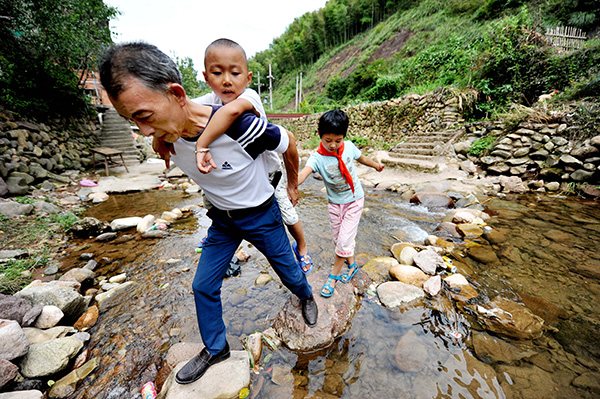 Two left-behind children follow their teacher to school in a mountainous area of Jiangxi province. (Zhuo Zhongwei/China Daily)