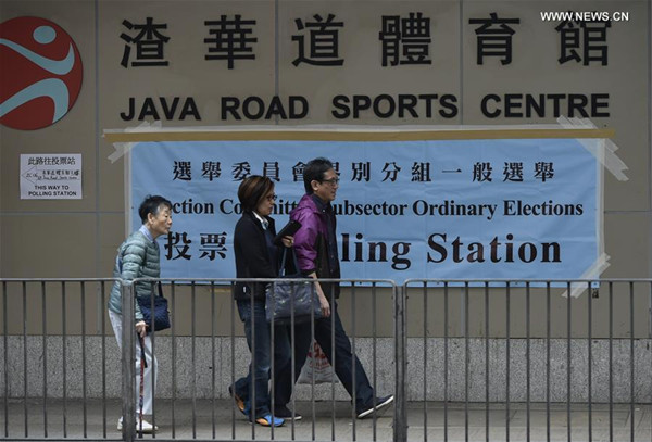 People walk near a polling station in Hong Kong, south China, Dec. 11, 2016. An election for the committee which is responsible for choosing the next Chief Executive of China's Hong Kong began on Sunday, during which more than 230,000 registered voters can cast their votes. (Xinhua/Wang Shen)