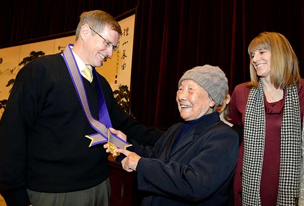 Stephen Brady, a family member of Richard Freeman Brady, a U.S. doctor who risked his life to save locals from Japanese troops during the Nanjing Massacre, meets Xia Shuqin, a massacre survivor, in Nanjing on Monday. Six foreigners, including Richard Freeman Brady and John Rabe, a German businessman who also protected locals, were honored with the Zijin Grass International Commemorative Medal of Peace ahead of Nanjing Massacre Remembrance Day on Tuesday. CUI XIAO/CHINA DAILY