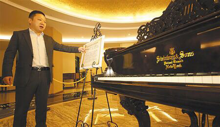Ye Hao with one of the 300 pianos he has collected which are now on display at the Chongqing Huangjueping Piano Musiem in Southwest China. (Photo by Tan Yingzi/chinadaily.com.cn)