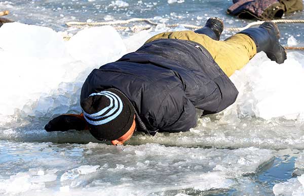 An ice collector drinks water from the Songhua River. (Photo By Zhang Qingyun / For China Daily)