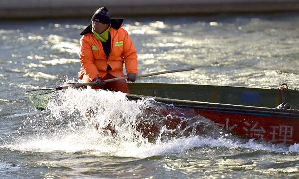 A worker collects garbage in the Haihe River in Tianjin on Dec 8. (Photo/Xinhua)