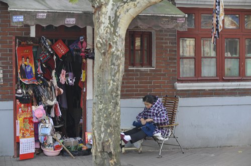 A woman knits in front of her sundries supply stall. (Photo/GT)
