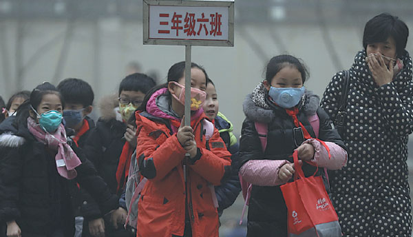 Primary school students wearing masks leave a school in Shijiazhuang, Hebei province, on Tuesday. The city, which had the worst air quality in November among 74 major cities monitored, ordered classes suspended on Wednesday. Zhu Xingxin / China Daily