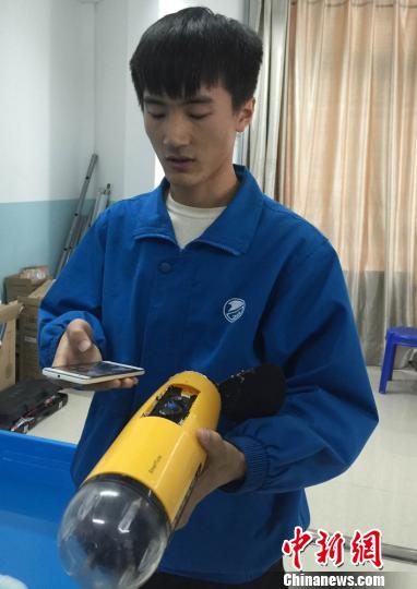 A student controls the robot fish with a mobile phone. (Photo: Chinanews.com/Liu Yutao)