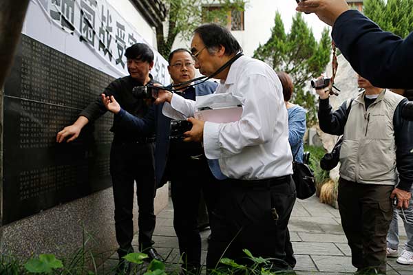 Japanese lawyer Keiichiro Ichinose (right) at the Quzhou Germ Warfare Victims Memorial Museum in Zhejiang in October as he takes a photo of a list of those who died as a result of Japan's biological weapons. (Photo by Han Qiang/For China Daily)