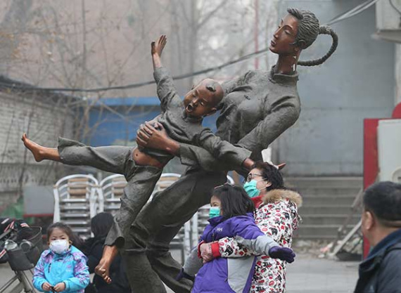 A mother and daughter wear masks as they pose with a statue in Beijing's Wangjing area on Sunday. Photo: WANG ZHUANGFEI/CHINA DAILY)