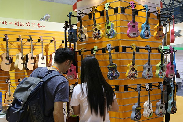 Two visitors take a close look at the ukuleles on display at a musical instruments exhibition in Beijing. The guitar-like stringed instrument has become popular, particularly among the young people. (Photo/China Daily)
