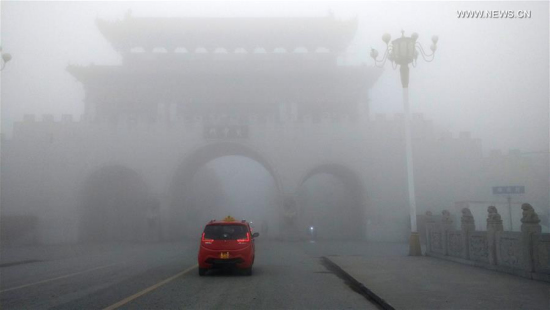 A car runs in the fog-bound county seat of Runan, central China's Henan Province, Jan. 3, 2017. A red alert for fog in large parts of China was issued by the National Meteorological Center on Tuesday. (Photo: Xinhua/Sun Kai)