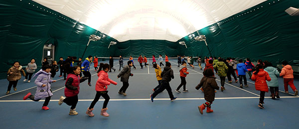 Students in a primary school in Shijiazhuang, capital of Hebei province, have their physical education class on Wednesday in a gym covered with an air cleaning system. (Photo by WANG XIAO/XINHUA)