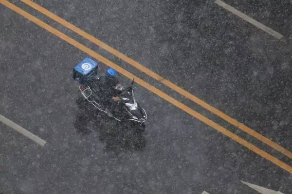 A deliveryman makes his way down the road in Beijing on a snowy day. (Photo from the web)