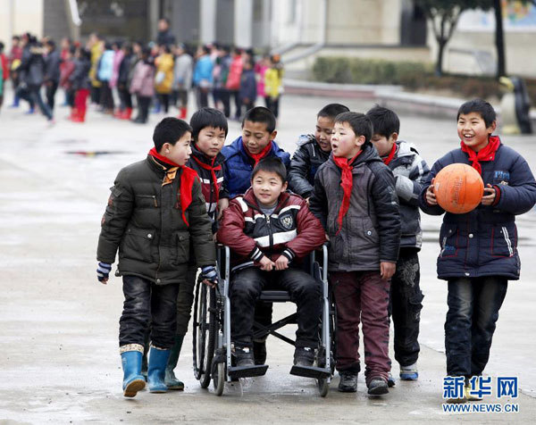 A group of students push Cheng Dongdong in a wheelchair at the primary school at Qiucun town in Guangde county, East China's Anhui province, on March 1, 2012. (Photo/Xinhua)